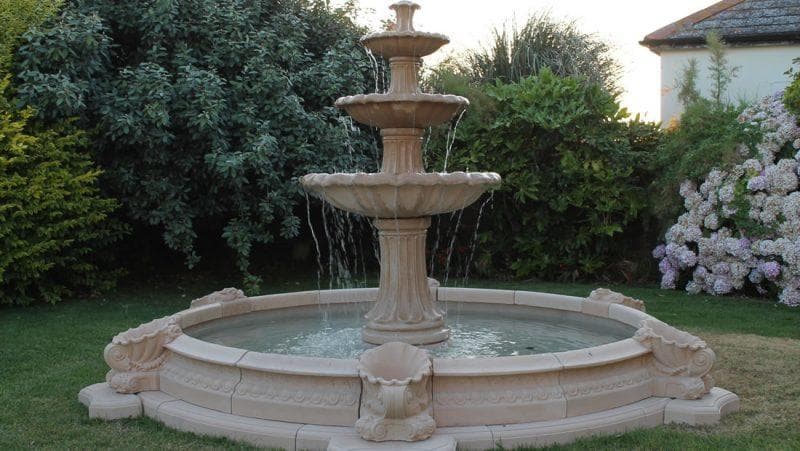 A tiered stone fountain in a landscaped garden