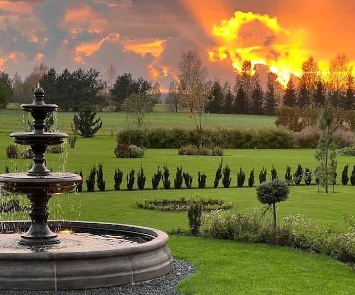 A tiered stone fountain in a landscaped garden at sunset