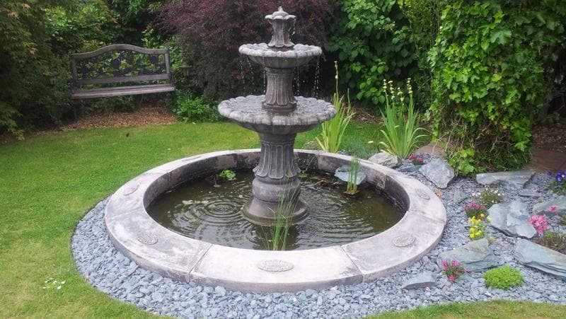 A low in-ground fountain surrounded by paving and planting