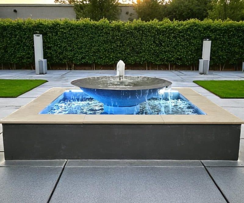 A modern illuminated composite fountain with a raised square pool