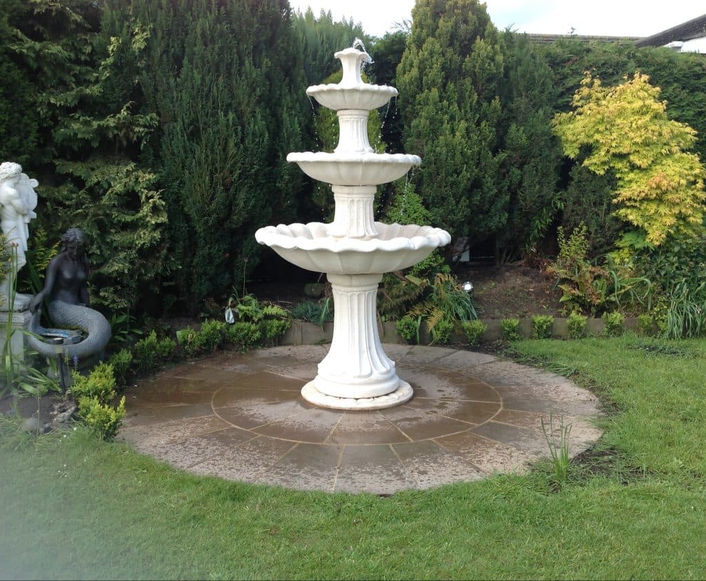A three-tiered self-contained fountain on a garden patio