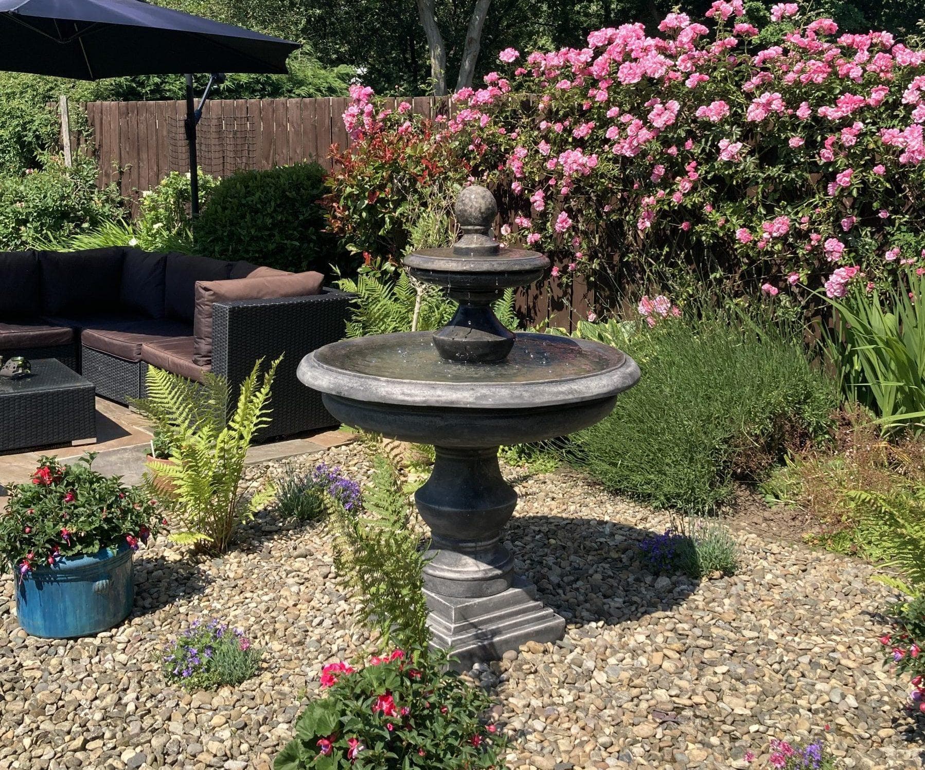 A tiered stone fountain running in a landscaped garden