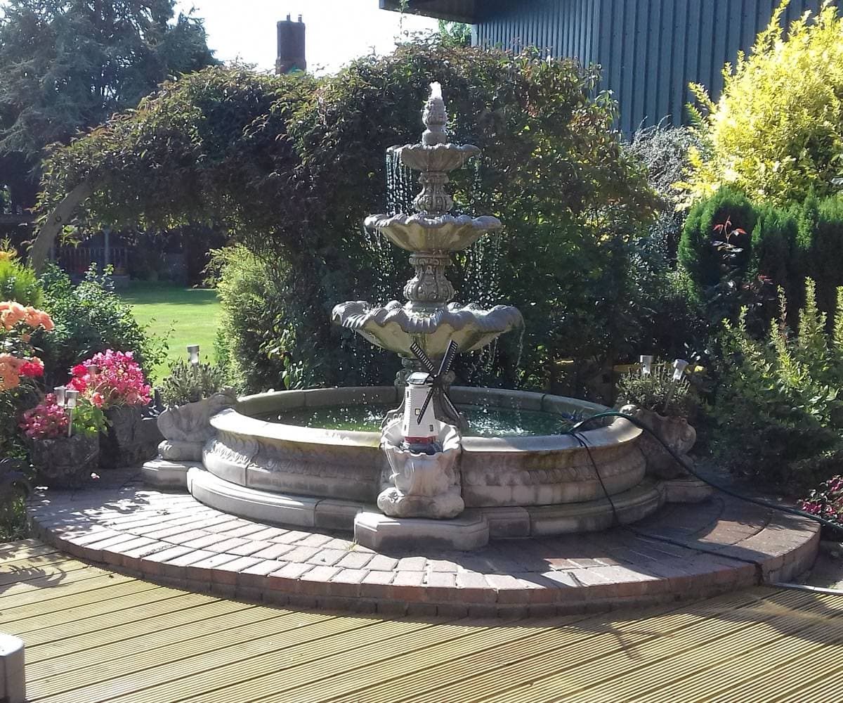 A grand tiered stone fountain with a full pool surround in a formal garden
